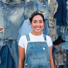 Young female college student posing in front of a denim backrop